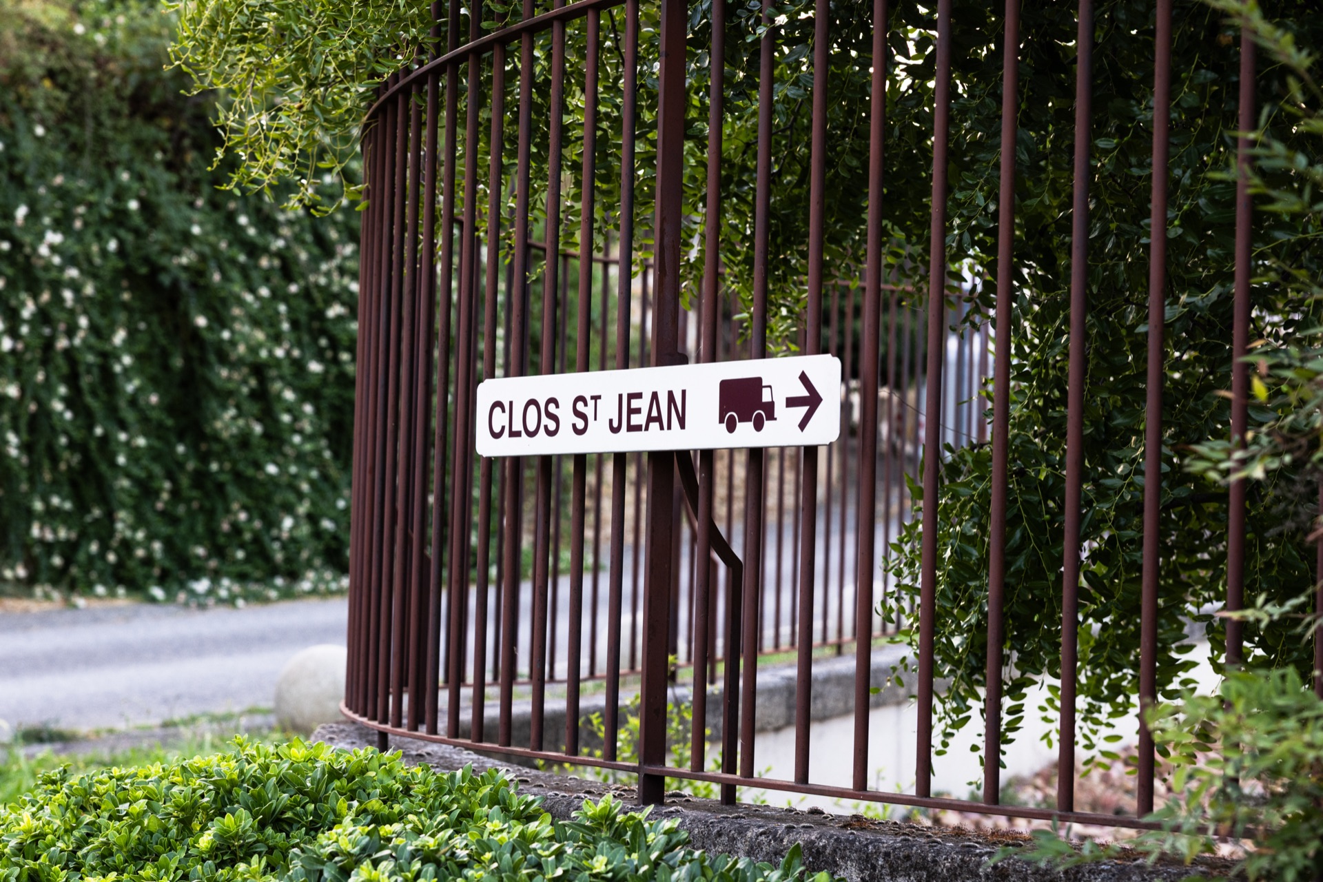 A delivery sign for Clos St Jean fixed to the railing at the estate entrance