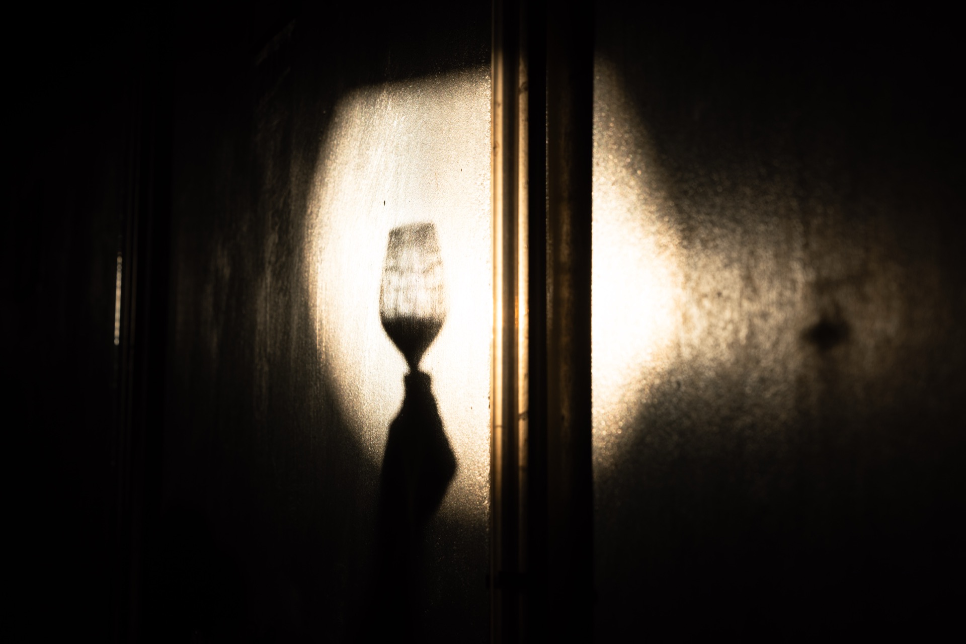 The shadow of a held glass thrown against the cellar wall