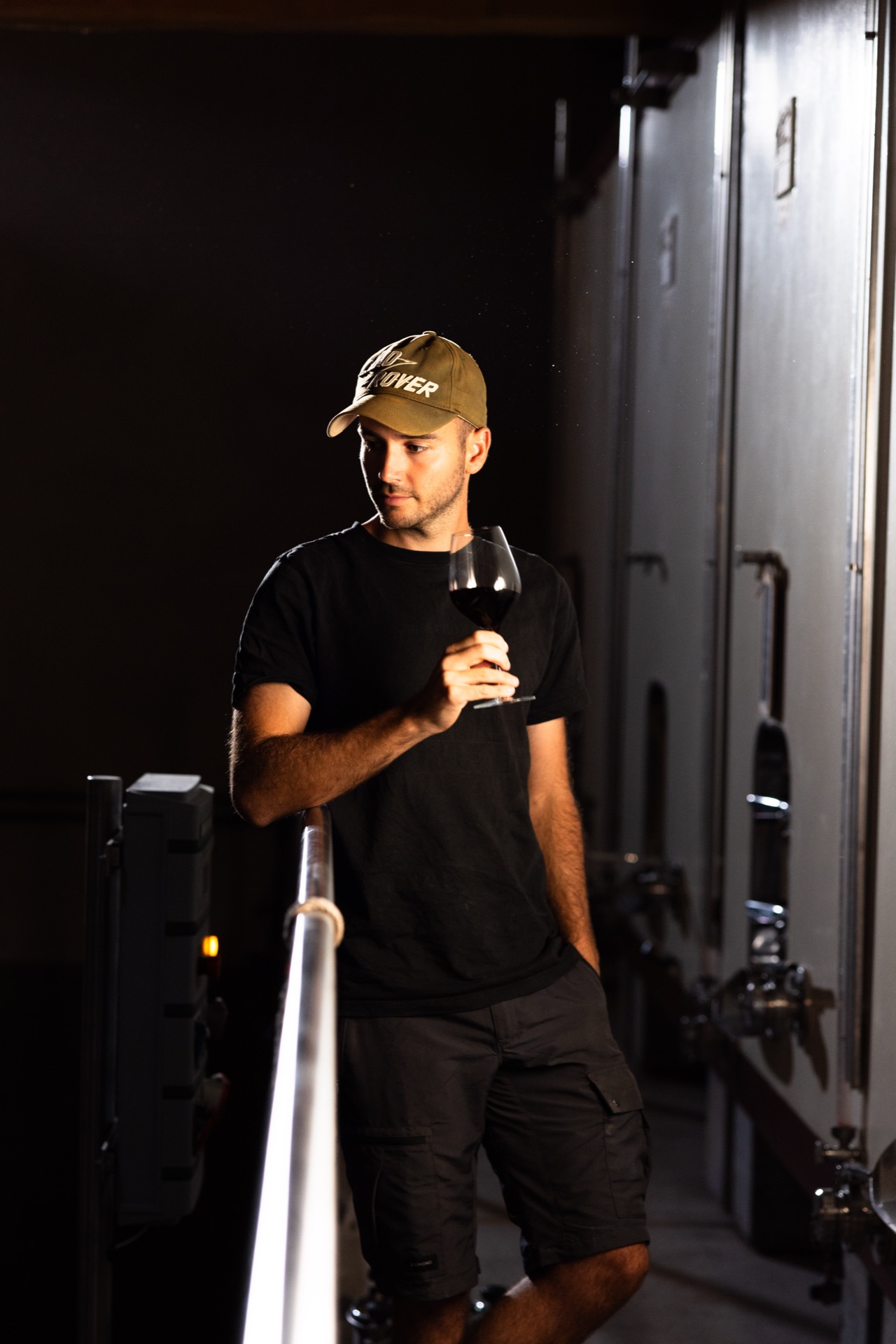 Tasting a glass drawn from the tanks in the low light of the cellar