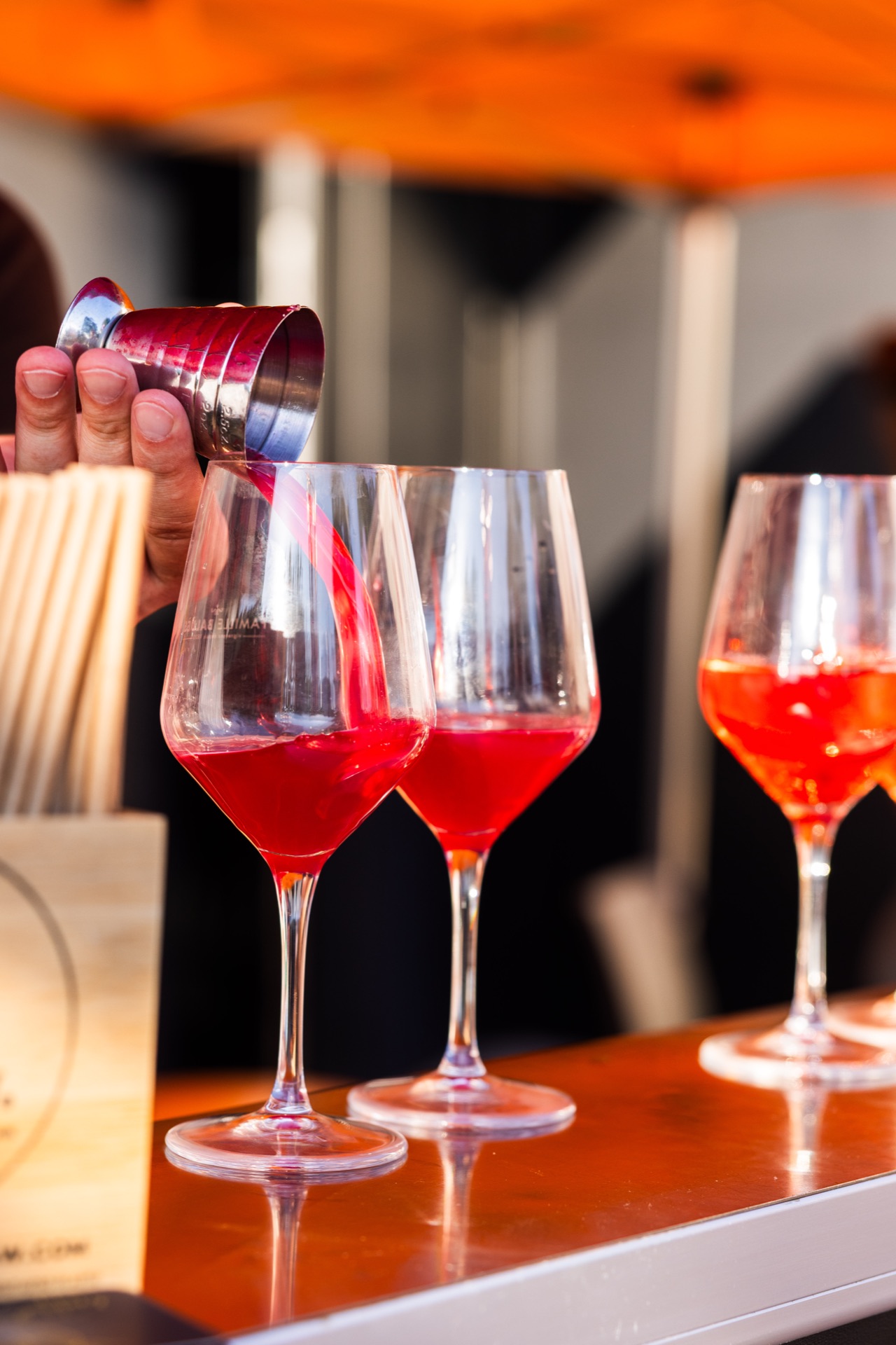 A red aperitif poured into waiting glasses on the bar