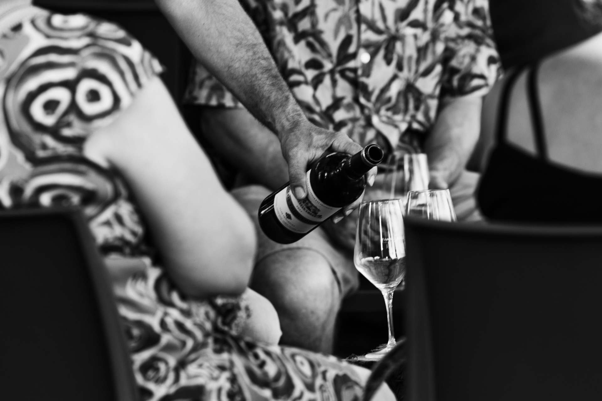 Black and white frame of a bottle being poured among seated guests