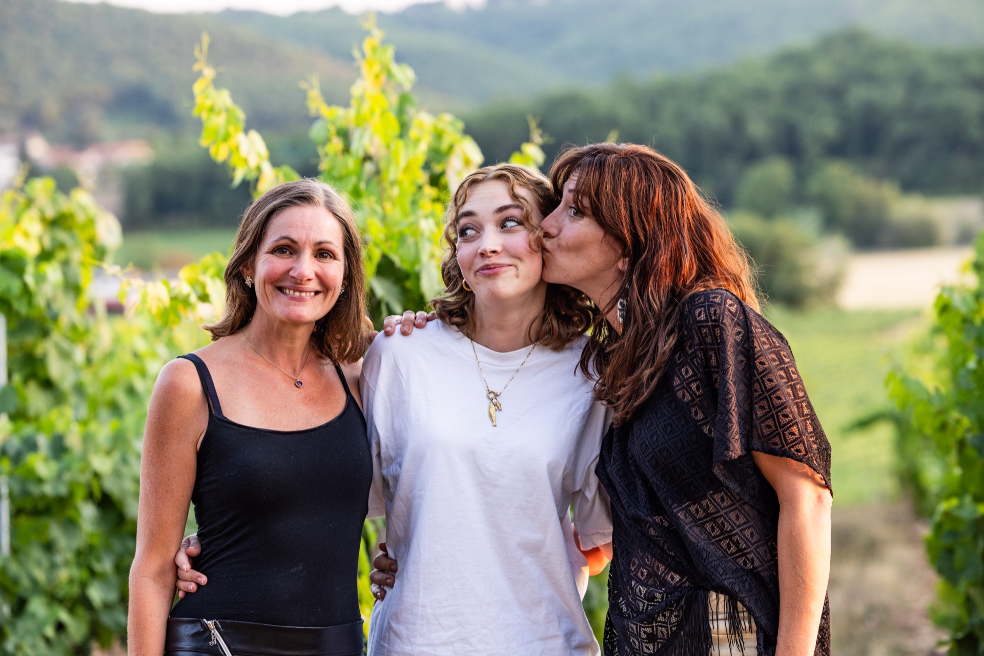 Portrait of three guests together in the vine rows at dusk