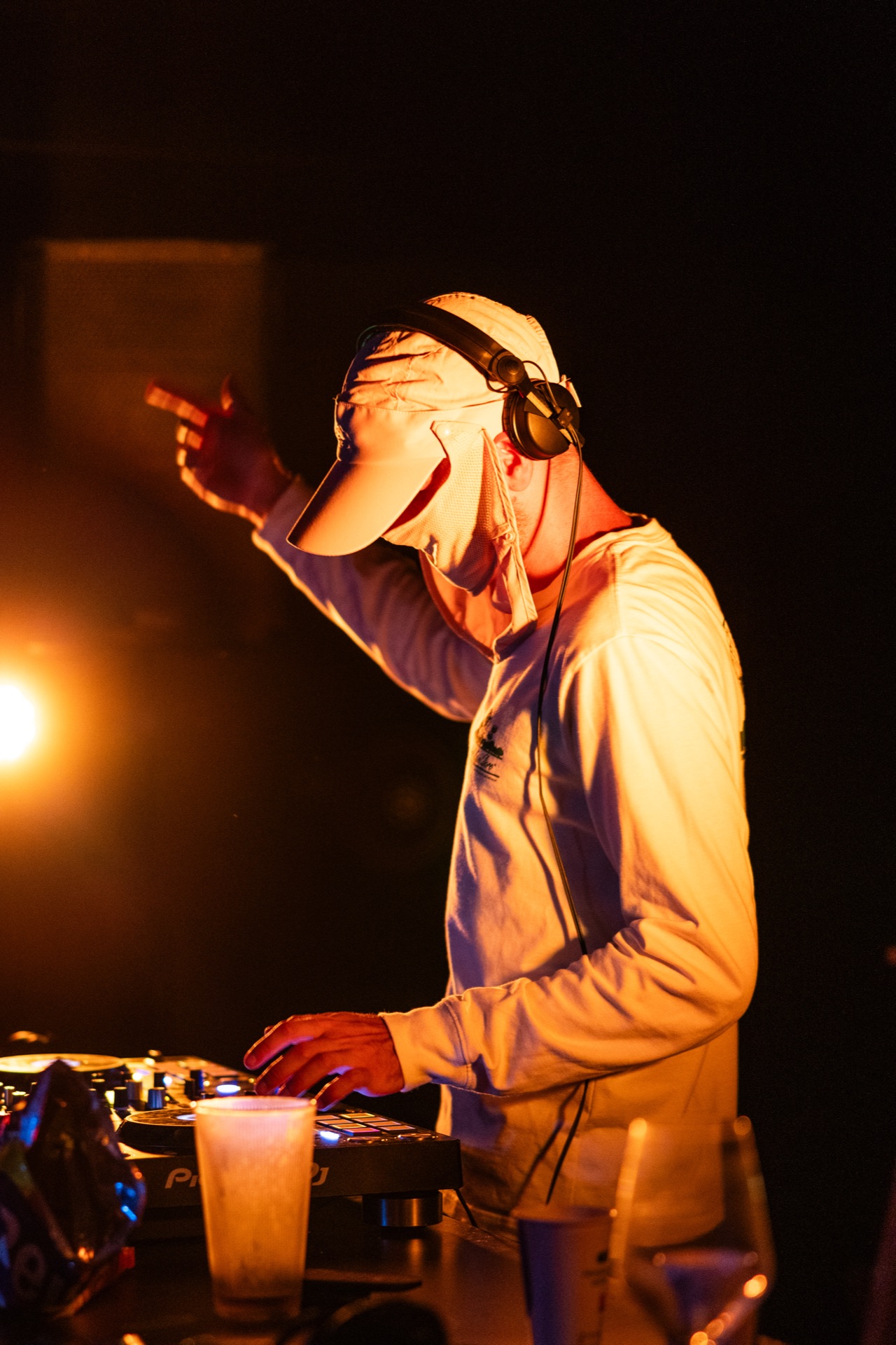 The DJ lit in warm orange, arm raised to the crowd