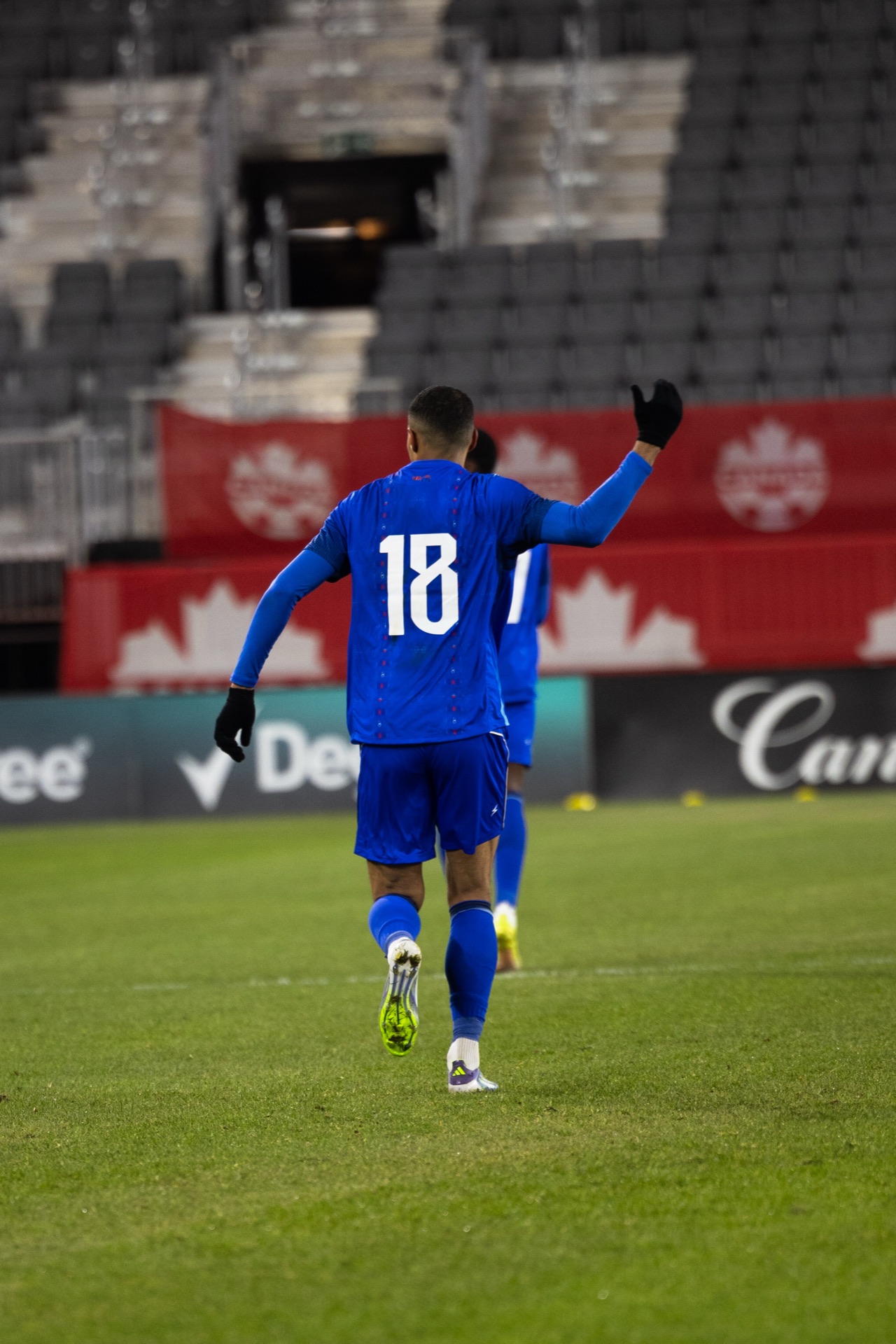 Isidor from behind, the number 18 across his shoulders, one gloved hand raised to call for the ball