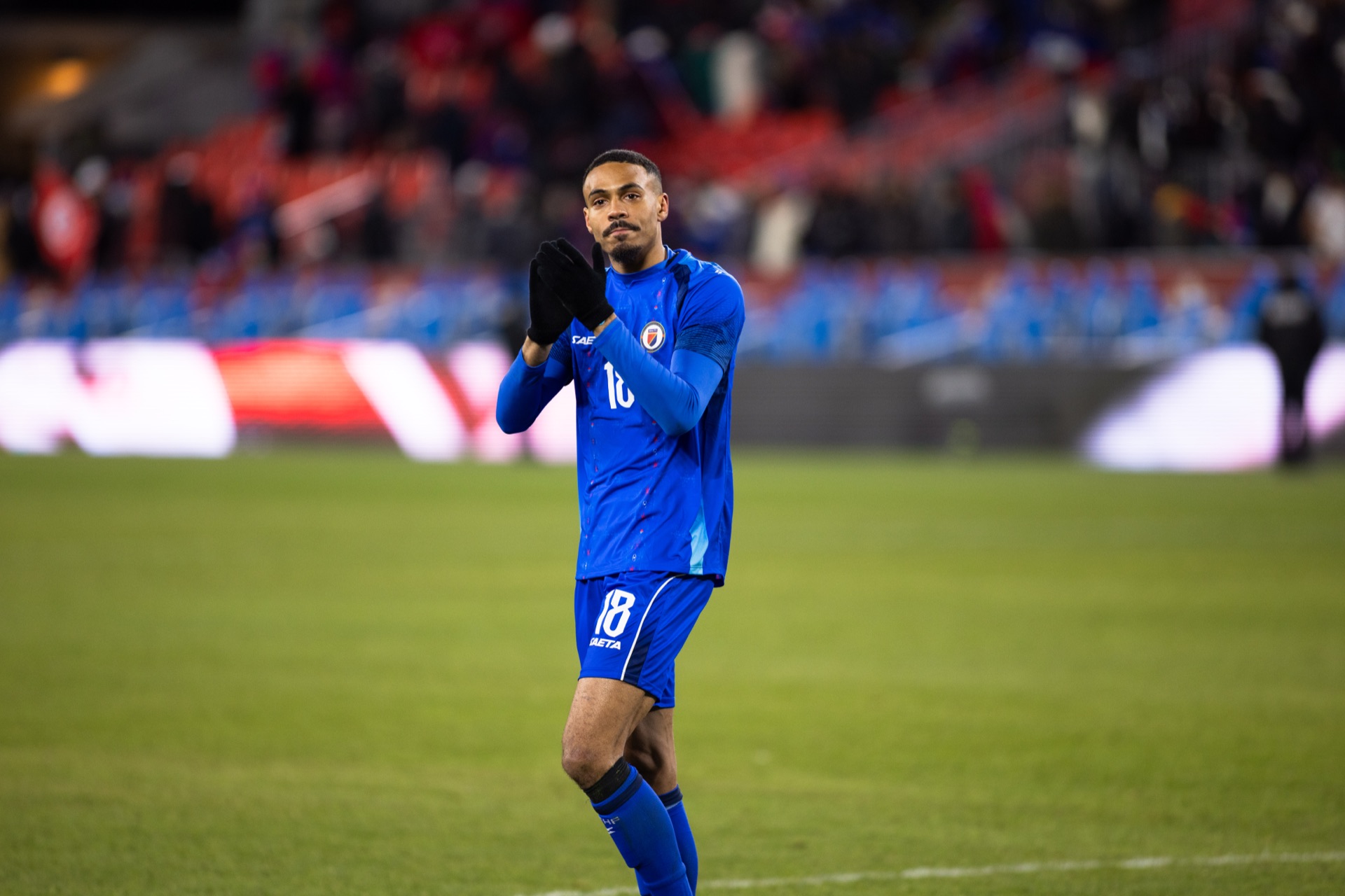 Isidor applauding toward the stands, both gloved hands together