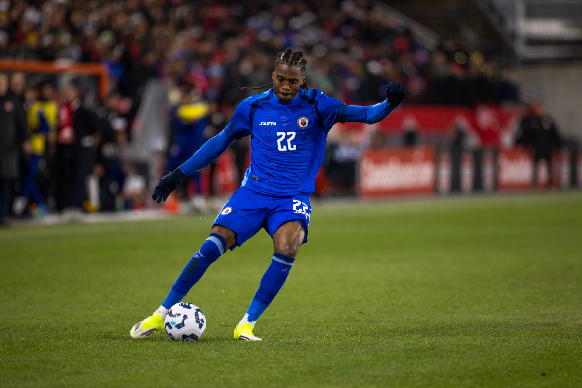 Haiti's number 22 leaning into a strike, planted foot dug into the grass