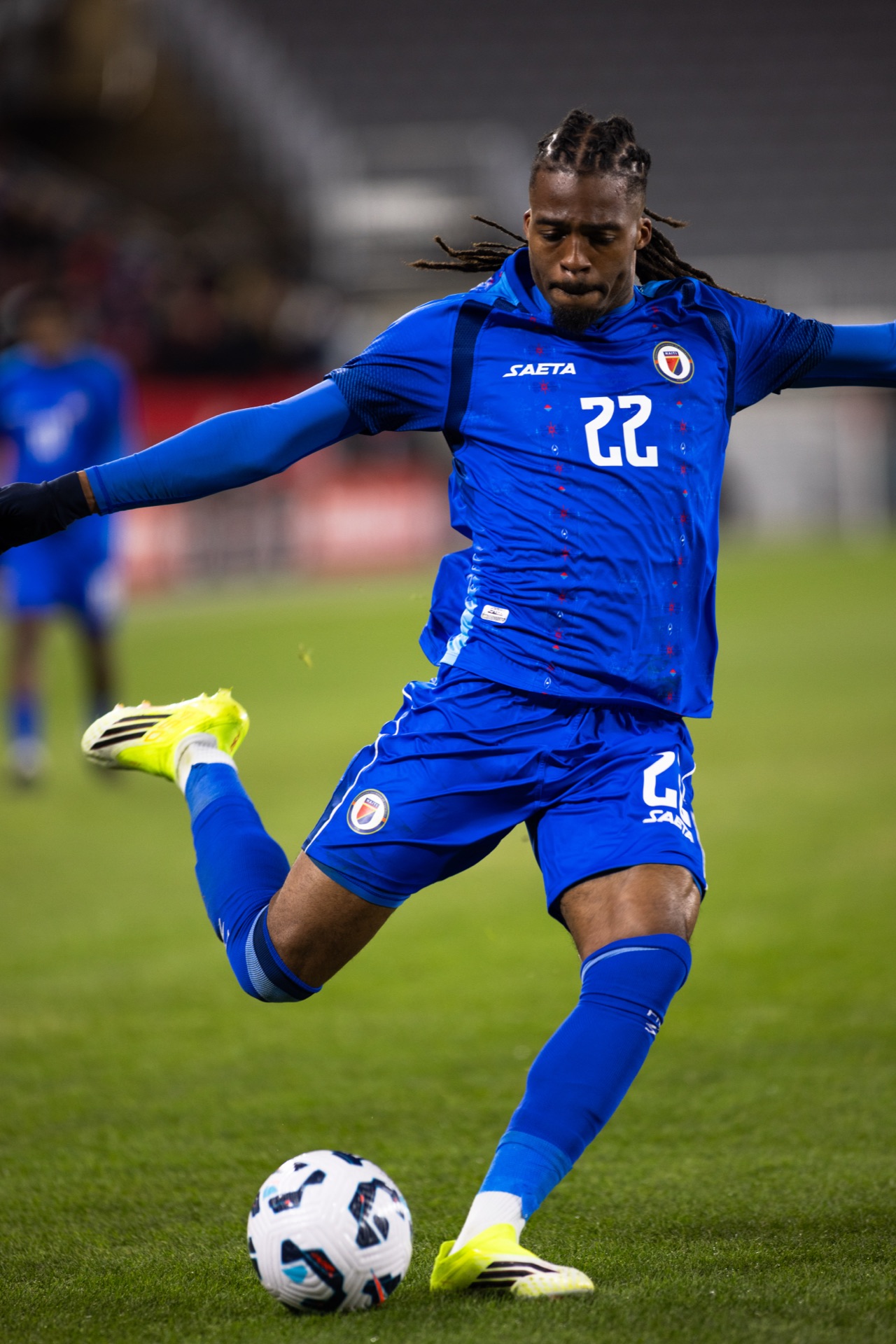 Haiti's number 22 mid-strike, arms wide for balance, in front of empty seats