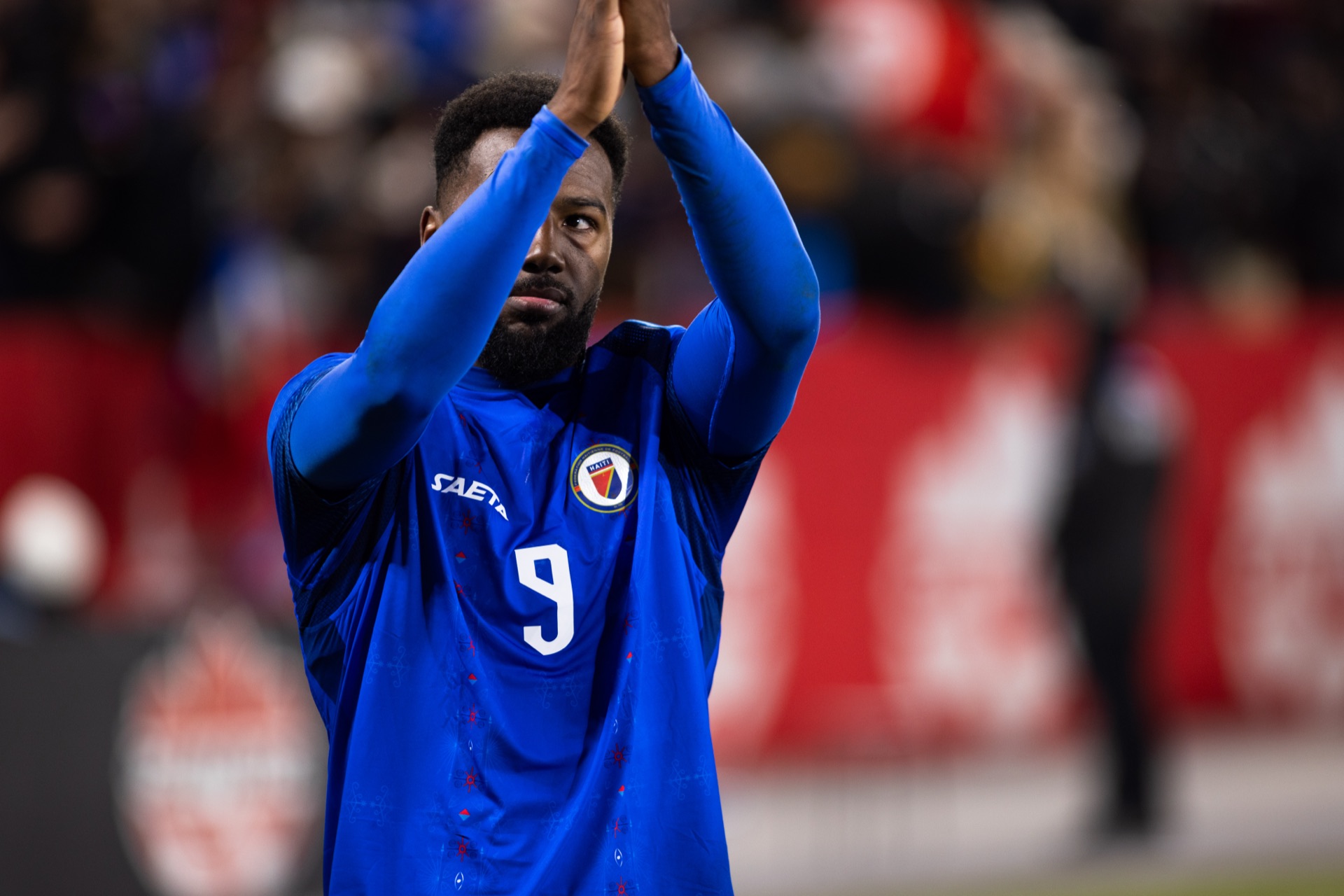 Haiti's number 9 applauding the stands with both hands raised in front of him