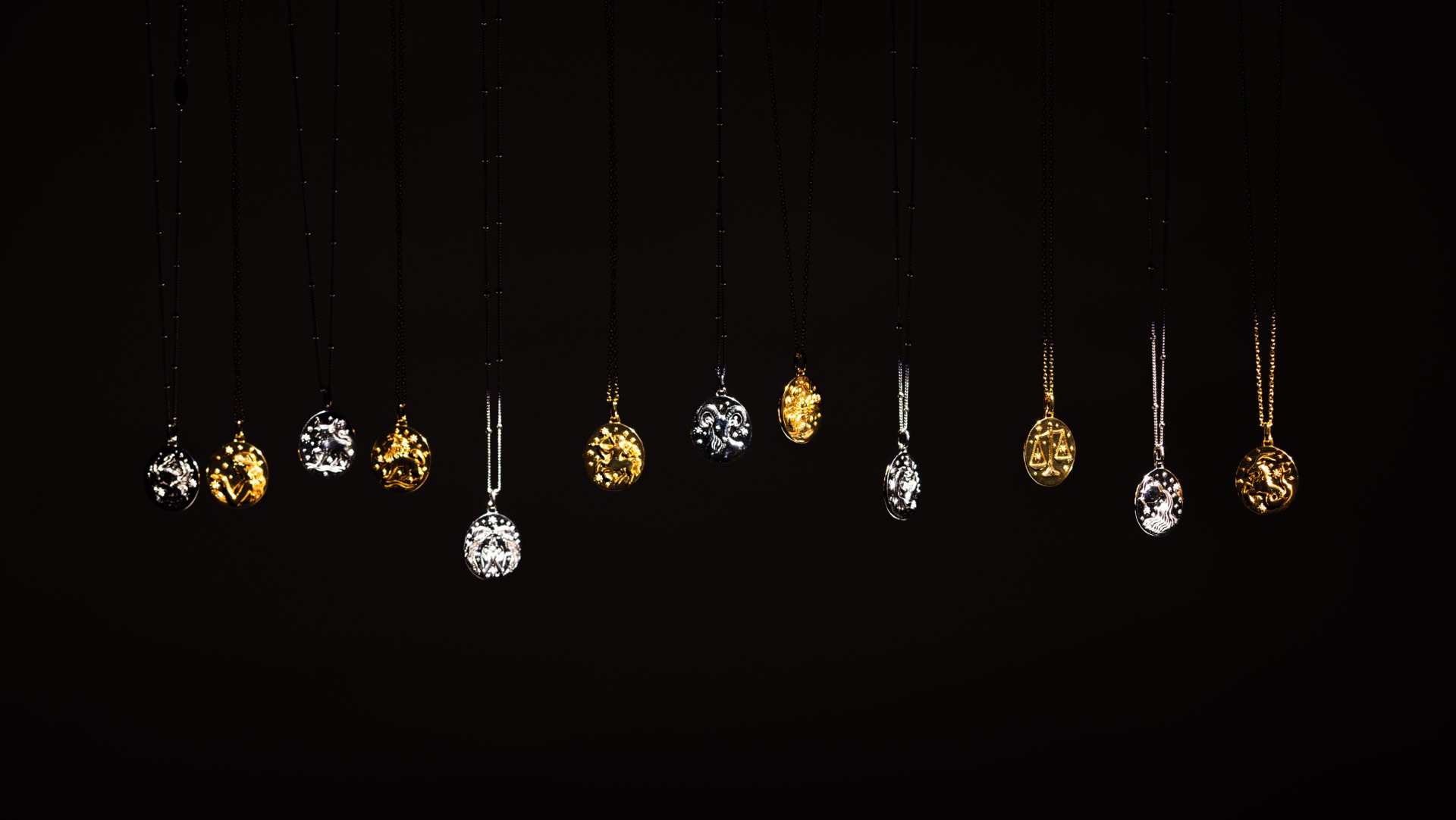 The run of Sacred Haven pendants hung in a row against black, gold and silver alternating