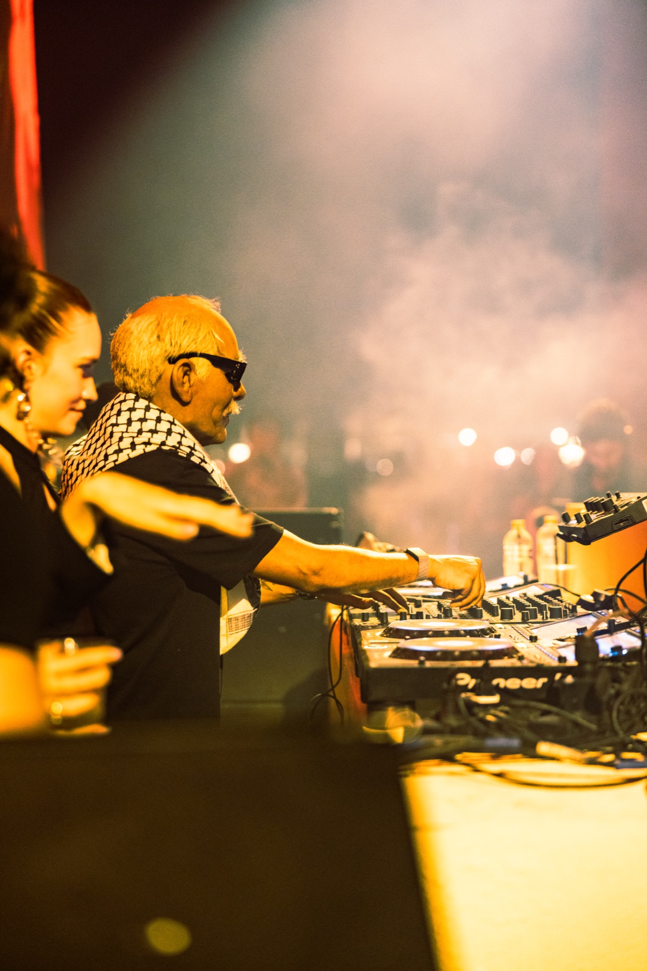 Doctor Alphonso working the decks in smoke and warm light
