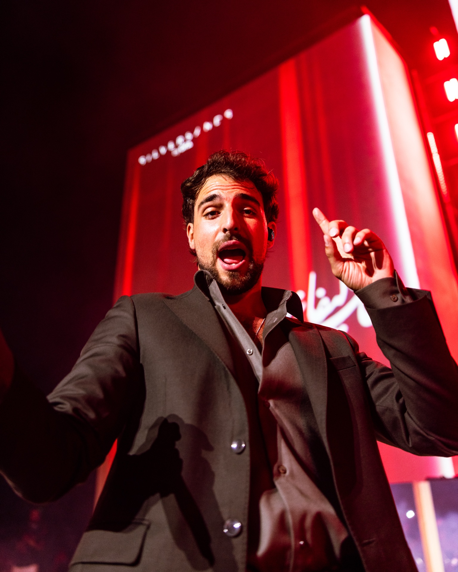 Saint Levant pointing out to the crowd, the screens burning red behind