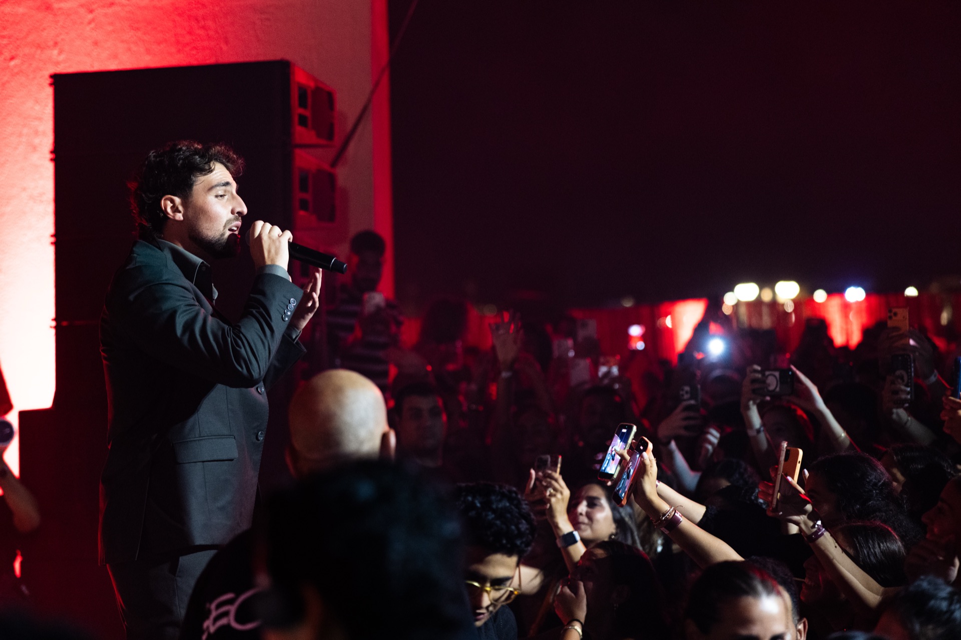 The crowd in red, phones up, the stage running off to the left