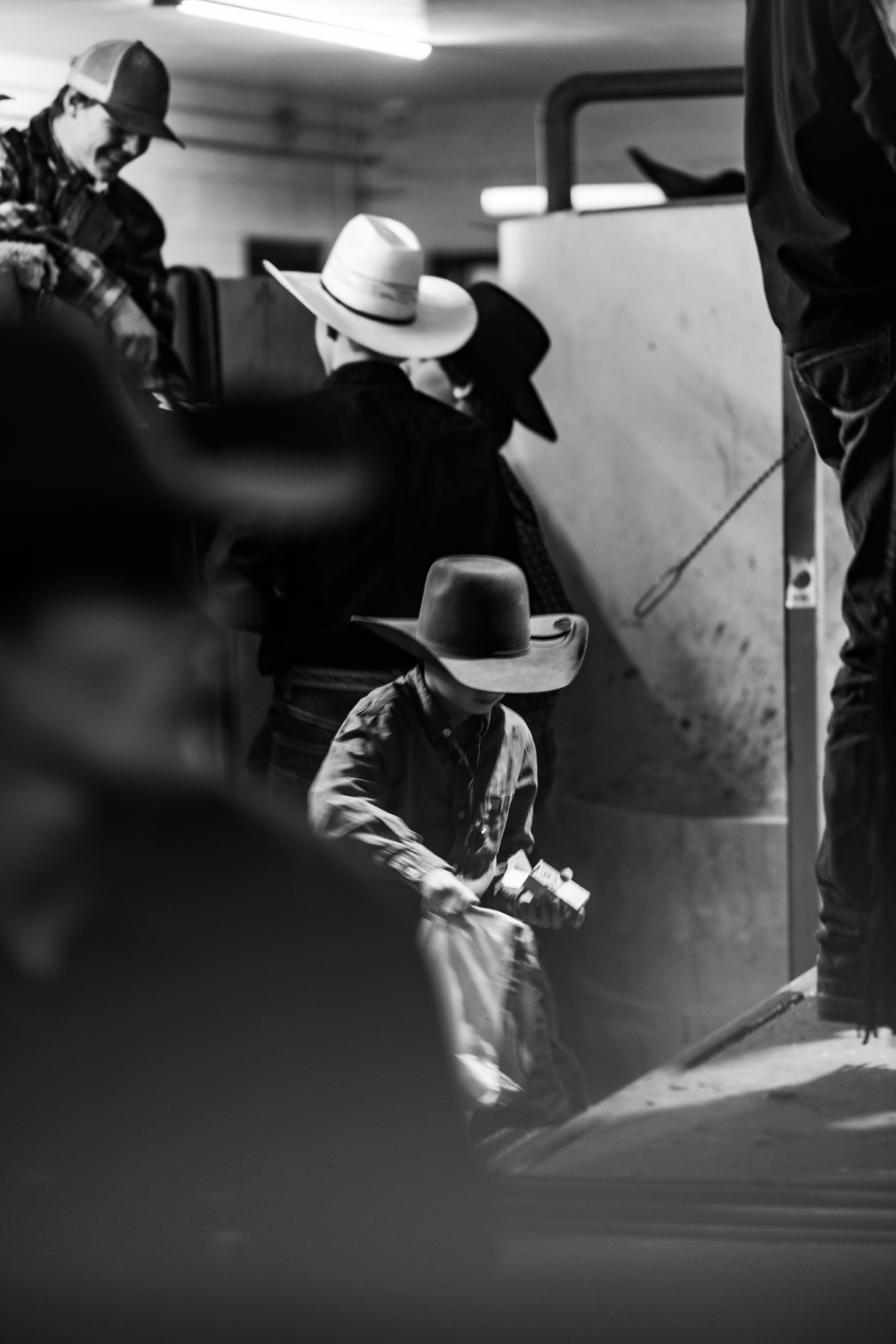 A young competitor in a felt hat readies his gear in the crowded back passage, figures blurred in the foreground