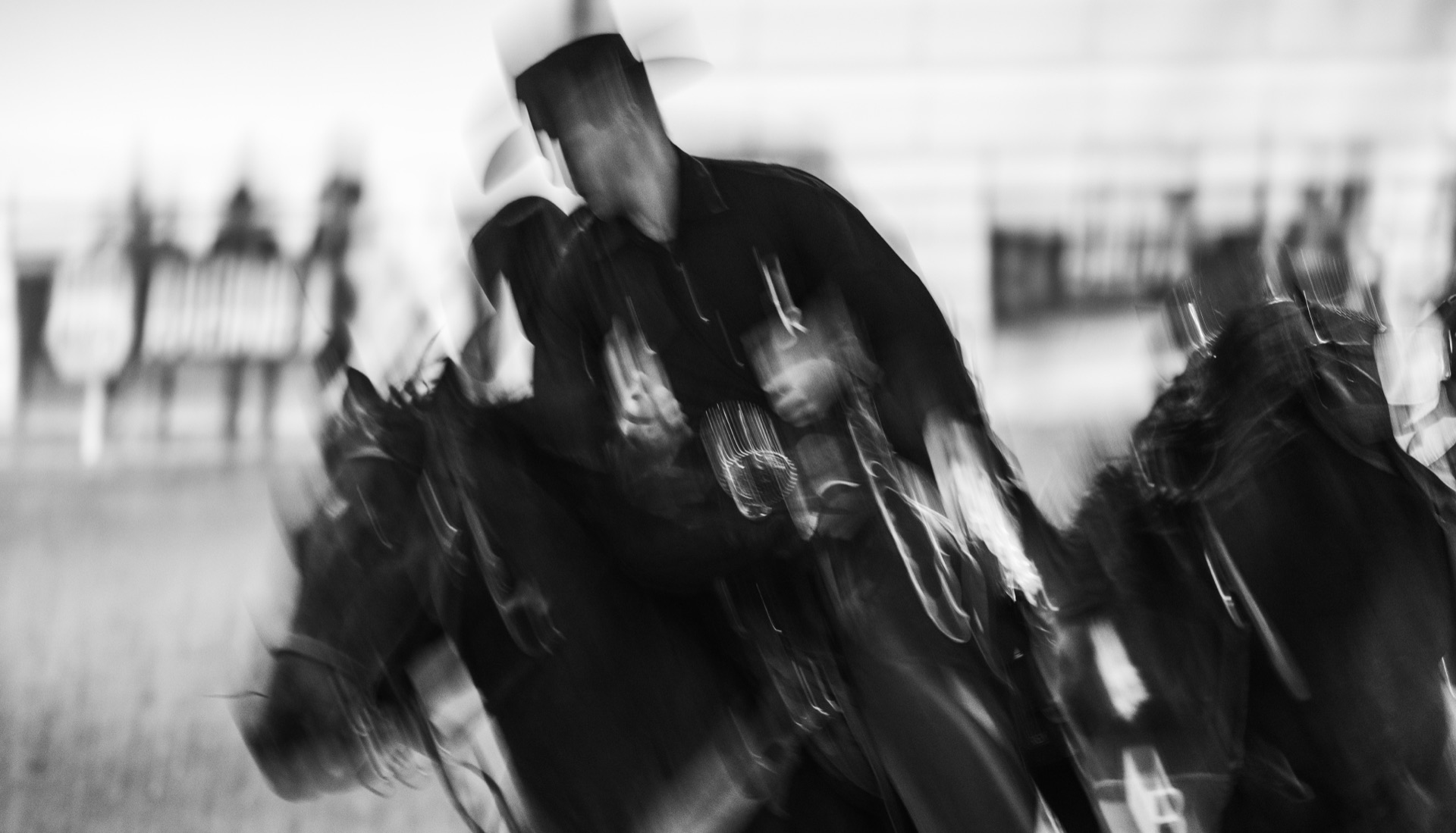 A long-exposure blur of mounted riders moving across the arena