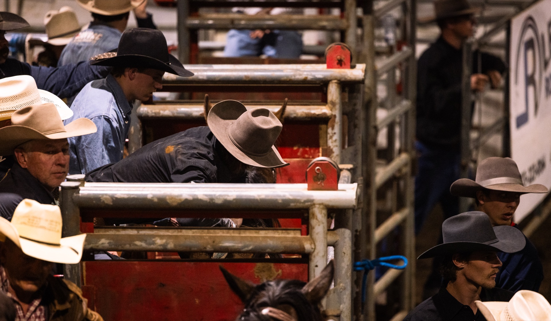 Cowboys wait shoulder to shoulder along the chutes, hats in a row
